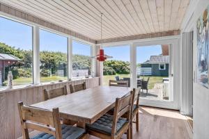 a dining room with a wooden table and windows at 355-Hvide-Sande-Fyrmarken-54 in Hvide Sande +27 photos