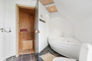 a bathroom with a white tub and a toilet at 5537-Hvide-Sande-Vesterledvej-14 in Havrvig +28 photos
