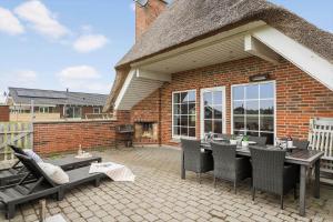 a patio with a table and chairs and a building at 5537-Hvide-Sande-Vesterledvej-14 in Havrvig