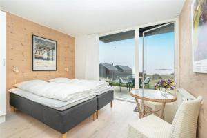 a bedroom with a bed and a table and a balcony at 717-Hvide-Sande-Slusen-17 in Hvide Sande