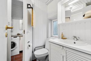 a white bathroom with a toilet and a sink at 602-Hvide-Sande-Nygardsvej-32 in Bjerregård
