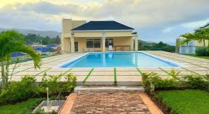 a house with a swimming pool in front of it at The Full Maison at Ocho Rios in Ocho Rios