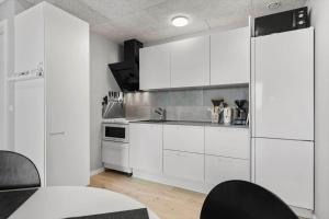a white kitchen with white cabinets and a table at 776-Hvide-Sande-Norregade-2-nr-27 in Hvide Sande
