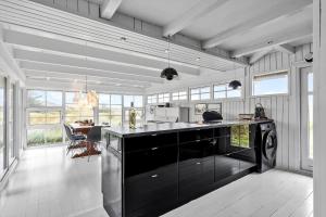 a kitchen with a black counter top and windows at 5507-Hvide-Sande-Tornbjerrevej-56 in Havrvig
