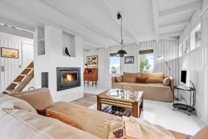a living room with a couch and a fireplace at 5507-Hvide-Sande-Tornbjerrevej-56 in Havrvig