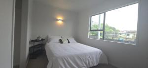 a white bedroom with a bed and a window at Paradise on Snells Beach in Snells Beach