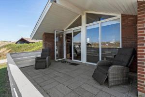 a patio with two chairs and windows on a house at 513-Hvide-Sande-Riskrogvej-16 in Havrvig