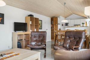 a living room with two leather chairs and a television at 6623-Hvide-Sande-Bilbergsvej-18 in Bjerregård