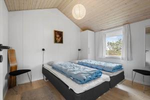 a bedroom with a bed with blue pillows on it at 6623-Hvide-Sande-Bilbergsvej-18 in Bjerregård