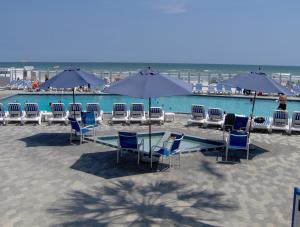 Islander Beach Resort - New Smyrna Beach في نيو سميرنا بيتش: مجموعة من الكراسي والطاولات والمظلات على الشاطئ