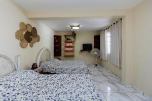 a bedroom with two beds and a window and a fan at Chácara Recanto do Sossego in Morretes