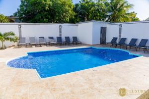 a swimming pool with chairs and a building at Luxury GuestHouse Suites in Cap-Haïtien