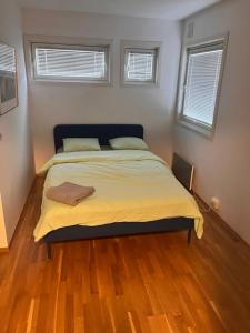 a bedroom with a bed with yellow sheets and two windows at Klaus torgårds vei 8b in Oslo