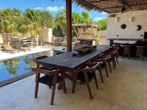 a wooden table and chairs next to a swimming pool at Flamingo Blue - Casa Boutique - Adults Only in El Cuyo