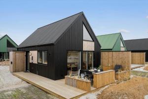 a black house with a black roof and a wooden deck at 9953-Hvide-Sande-Langsand-212 in Hvide Sande