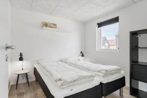 a white bedroom with two beds and a window at 947-Hvide-Sande-Langsand-228 in Hvide Sande