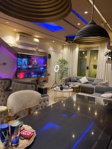 a living room with a table and a tv at شقه فندقيهTv75-PS4حدايق الاهراماتPyramids in ‘Ezbet `Abd el-Ḥamîd