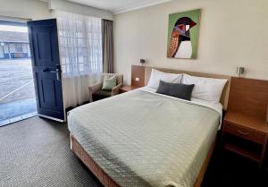 a hotel room with a bed and a chair at Colonial Terrace Motor Inn in Raymond Terrace