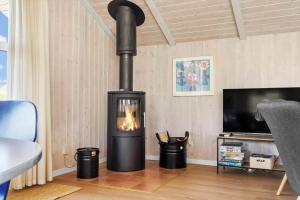 a black fireplace in a living room with a tv at 5526-Hvide-Sande-Baunebjergvej-29-A in Havrvig