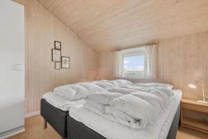 a large white bed in a room with a window at 5526-Hvide-Sande-Baunebjergvej-29-A in Havrvig