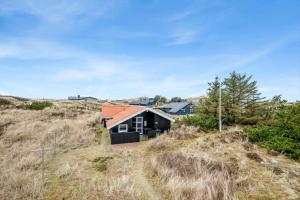 a black house with an orange roof on a hill at 5526-Hvide-Sande-Baunebjergvej-29-A in Havrvig