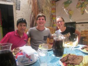 a group of three people sitting at a table with food at JaimeCrazyhostel in Huarmey