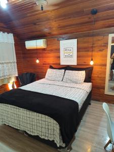 a bedroom with a bed in a room with wooden walls at Chalé suíte com ar em Resende in Resende