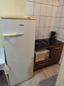 a white refrigerator in a kitchen with a microwave at Chalé suíte com ar em Resende in Resende