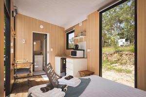 a room with a bed and a kitchen with a window at Maroota Greens SKY by Tiny Away in Maroota