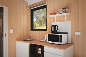 a kitchen with a microwave and a sink at Maroota Greens SKY by Tiny Away in Maroota