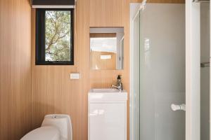 a bathroom with a toilet and a sink and a window at Maroota Greens SKY by Tiny Away in Maroota +17 photos