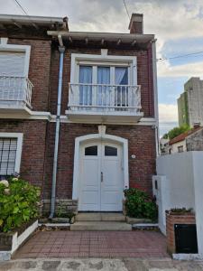 a brick house with a white door and a balcony at Amplio dpto Miramar centro y playa in Miramar +3 photos