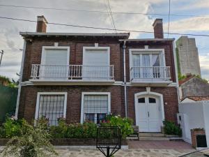 a brick house with white windows and a balcony at Amplio dpto Miramar centro y playa in Miramar