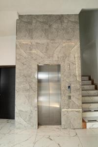 a metal elevator in a lobby with a stone wall at Hotel Harvest Retalhuleu in Santa Cruz Muluá