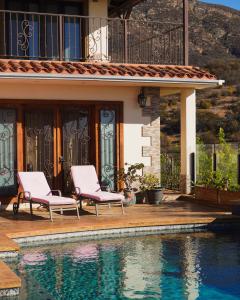 a house with two chairs next to a swimming pool at Hacienda Martlot in Ensenada