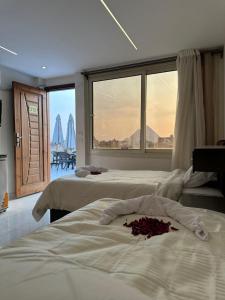 two beds in a room with a large window at sun 3 pyramids view hotel in Cairo