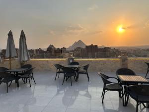 a patio with tables and chairs and a view of the pyramids at sun 3 pyramids view hotel in Cairo