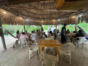 a group of people sitting at tables in a restaurant at Zirumake Tayrona Dentro del Parque Tayrona in El Zaino