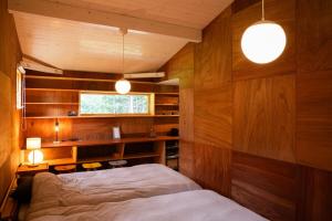a bedroom with wooden walls and a bed and a desk at White Bird in Hokuto