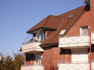 ビューズムにあるHaus Nordstrand Vereinsallee 21の白いバルコニーと茶色の屋根が特徴のレンガ造りの家