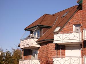 Casa de ladrillo con balcones blancos y techo marrón en Haus Nordstrand Vereinsalle 21WHG 2 6, en Büsum