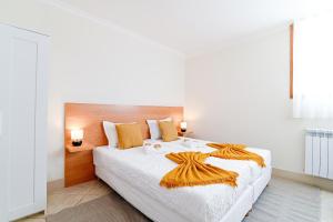 a bedroom with a large white bed with orange pillows at Casa Tomé de Sousa in Rates