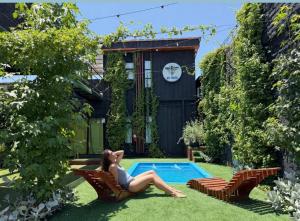 a woman sitting in a chair next to a pool at Casa Withe opción jacuzzi estadía villa alemana in Villa Alemana