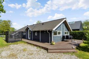 a blue tiny house with a wooden deck at FA066-Faxe-Ladeplads-Engsvinget-5 in Fakse Ladeplads