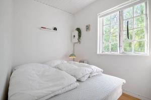 a white bed in a white room with a window at 2002-Stege-Solvgranen-7 in Stege