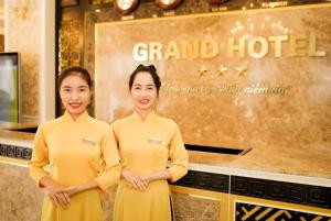 two women in yellow uniforms standing in a restaurant at Grand Hotel in Hòa Bình