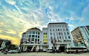 a large white building in a city with a cloudy sky at Grand Hotel in Hòa Bình