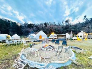 a group of tents in a field with a fire pit at KIBOTCHA/キボッチャ in Higashimatsushima