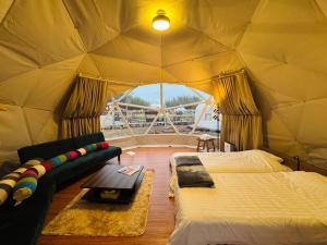 a room with a bed and a couch in a tent at KIBOTCHA/キボッチャ in Higashimatsushima