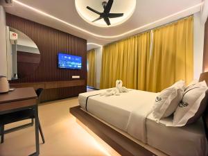 a bedroom with a bed and a desk and a television at Seeds Hotel Damansara Pelangi in Petaling Jaya